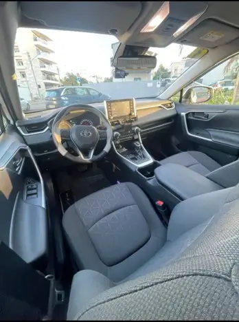 הסעות מכל יעד לנתב''ג - פנים מונית טויוטה RAV4, מבט מהצד על עמדת הנהג, ההגה ולוח המחוונים.