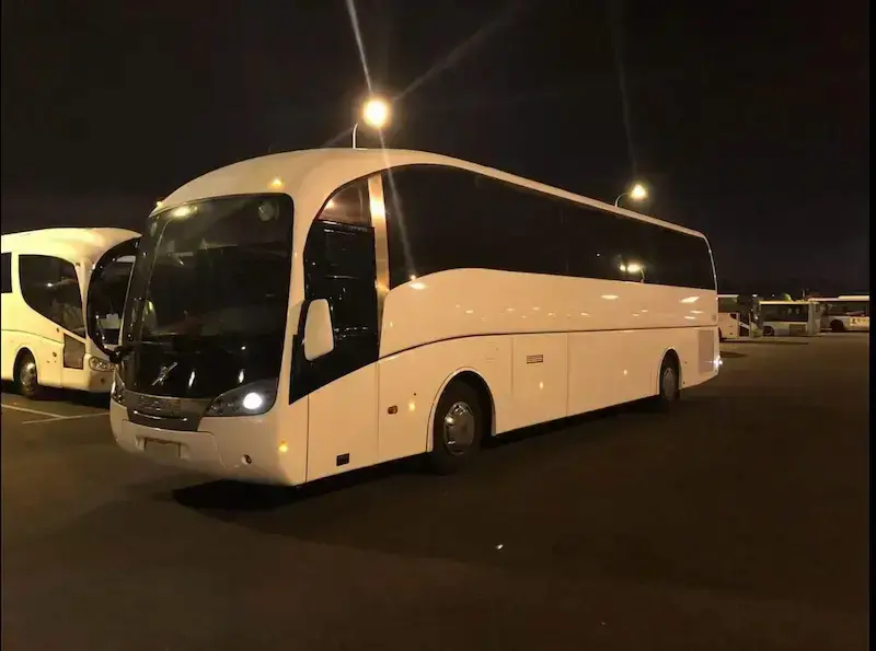אוטובוסים בפריסה ארצית - אוטובוס נוסעים גדול ומפואר בצבע לבן, חונה בחניון בשעות הלילה.