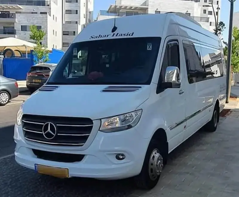 מיניבוס מכל יעד לנתב''ג - חזית וצד של מיניבוס מרצדס לבן וחדשני חונה ברחוב.